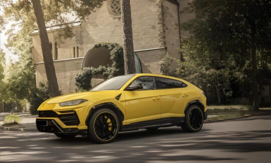 Yellow Lamborghini Urus parked on a sunny street in front of a historic building