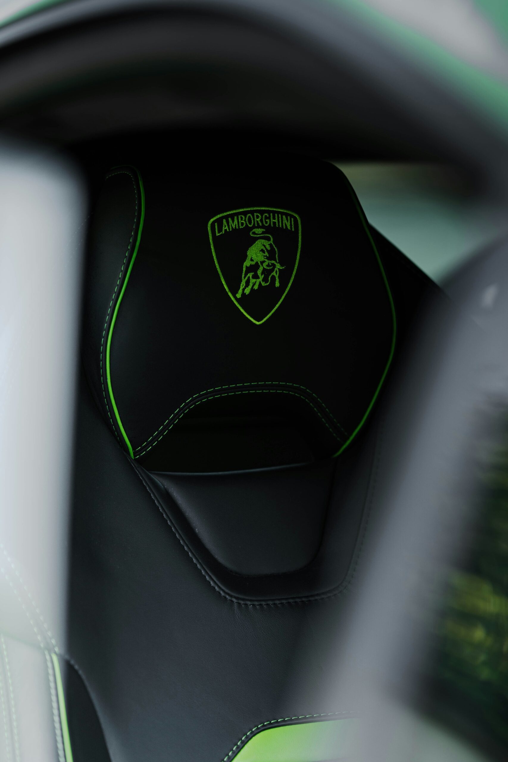 Close-up of Lamborghini Huracán sport seat with green stitching and embroidered logo — showcasing premium Italian craftsmanship and interior design.