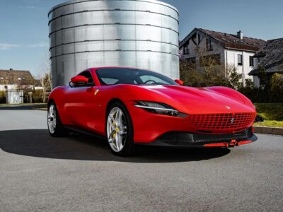 Ferrari Roma in red parked on a scenic road, showcasing its sleek design and powerful features