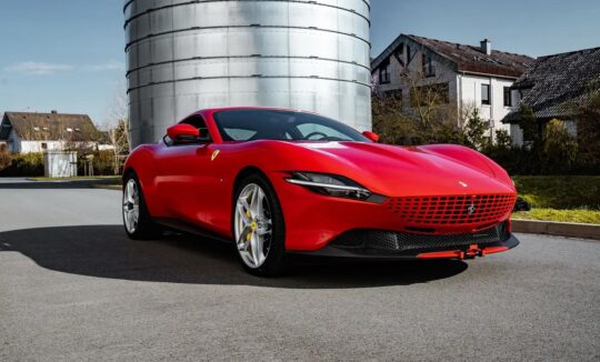 Ferrari Roma in red parked on a scenic road, showcasing its sleek design and powerful features