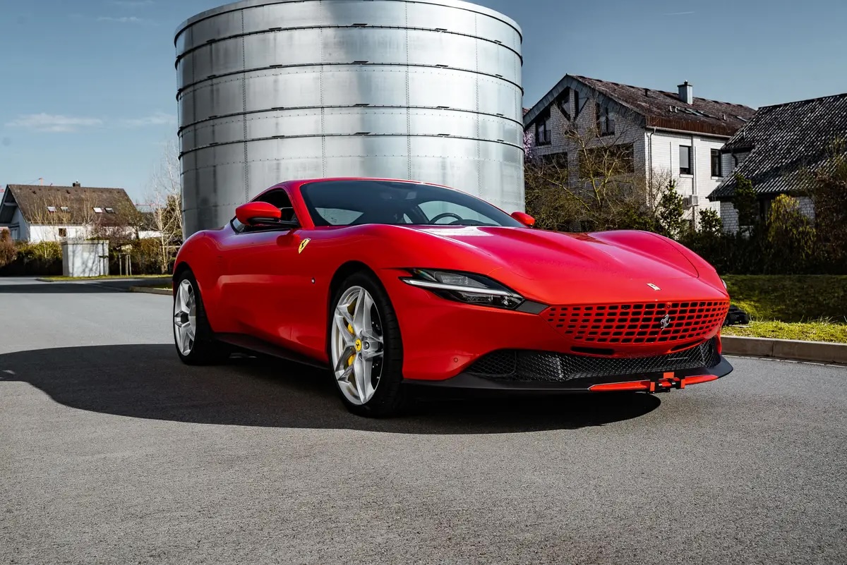Ferrari Roma in red parked on a scenic road, showcasing its sleek design and powerful features